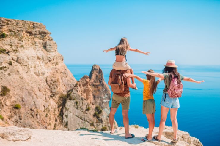 famiglia di spalle su montagna che vede il mare